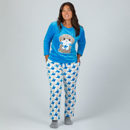 A woman wearing a blue long-sleeve top with an embroidered cute dog design and gray, blue and light blue houndstooth pattern. Design a grey dog with a scarf in super cozy fabric.