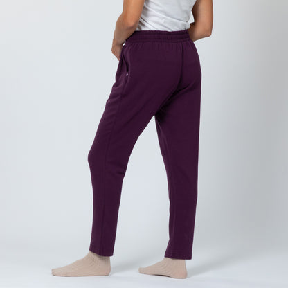 Person wearing plum colored casual pants on a white background.