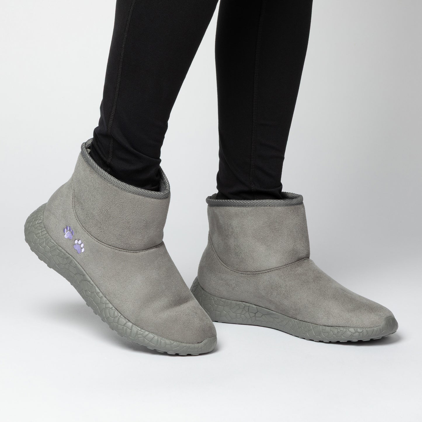 Gray slip-on boots worn with black leggings on a light gray background