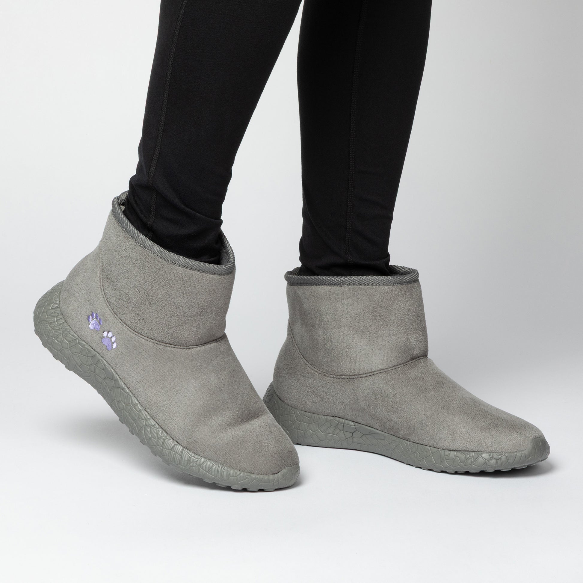 Gray slip-on boots worn with black leggings on a light gray background