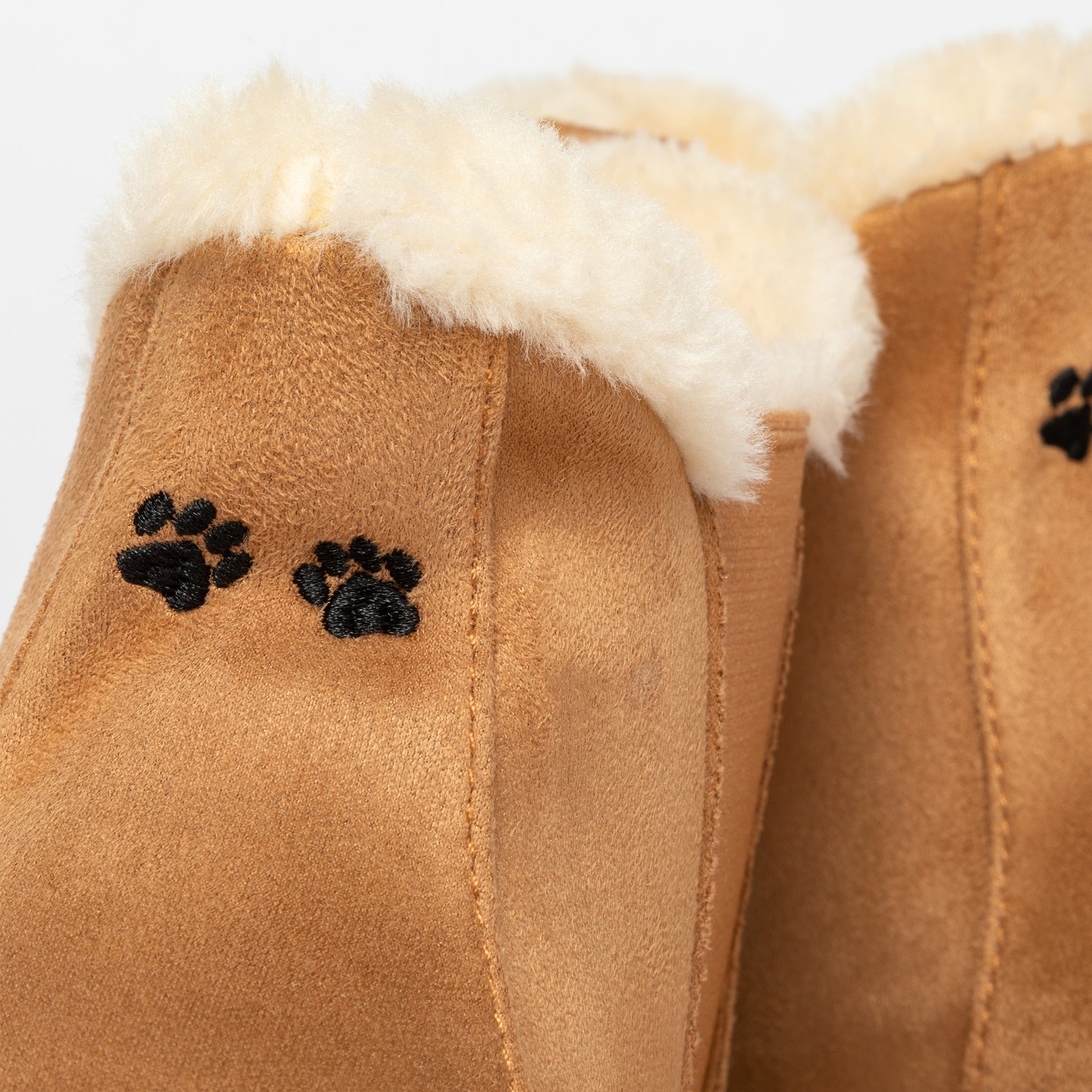 Brown slip on boots with white fur lining and black paw prints on a white background