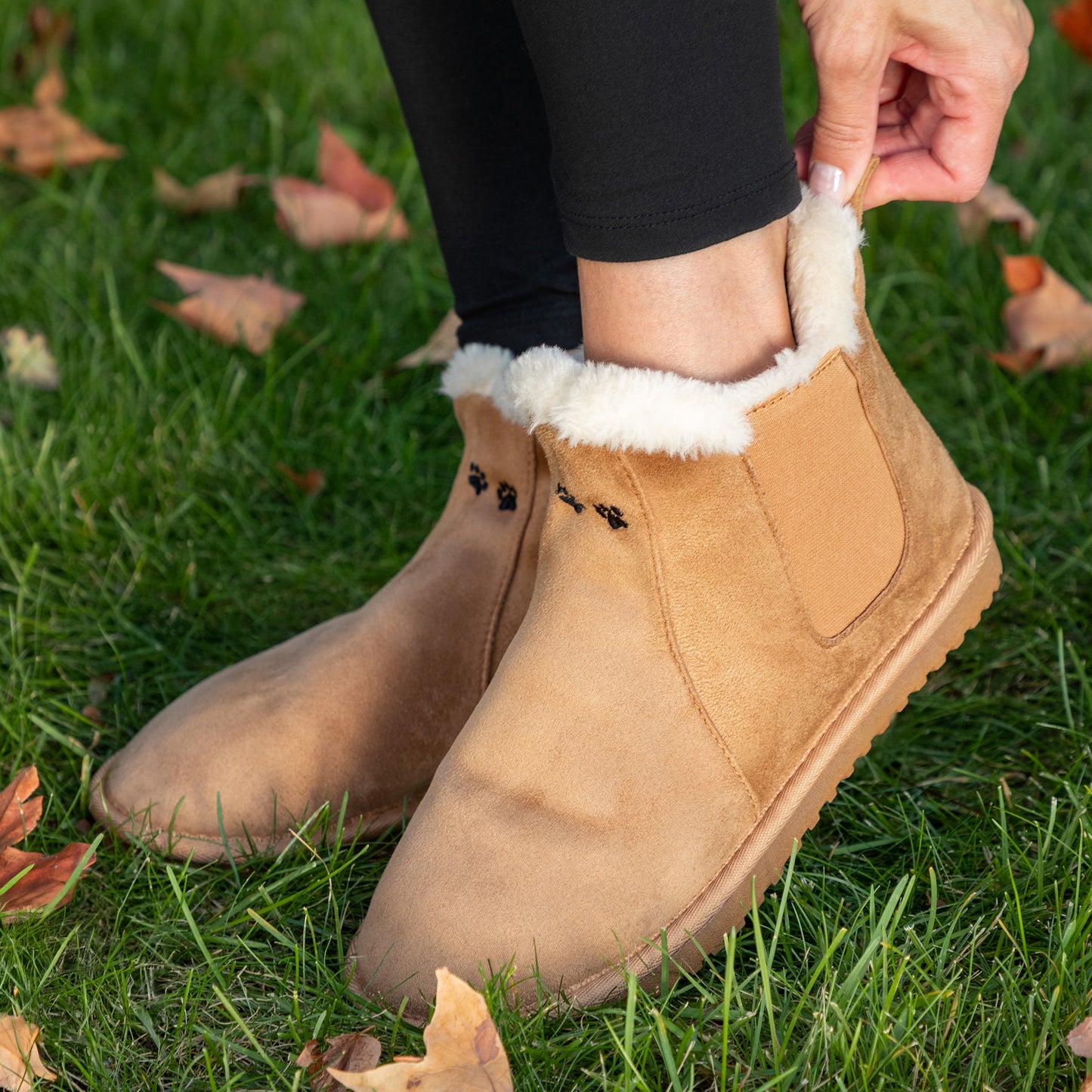 Tan suede boots with white fur lining worn on grass