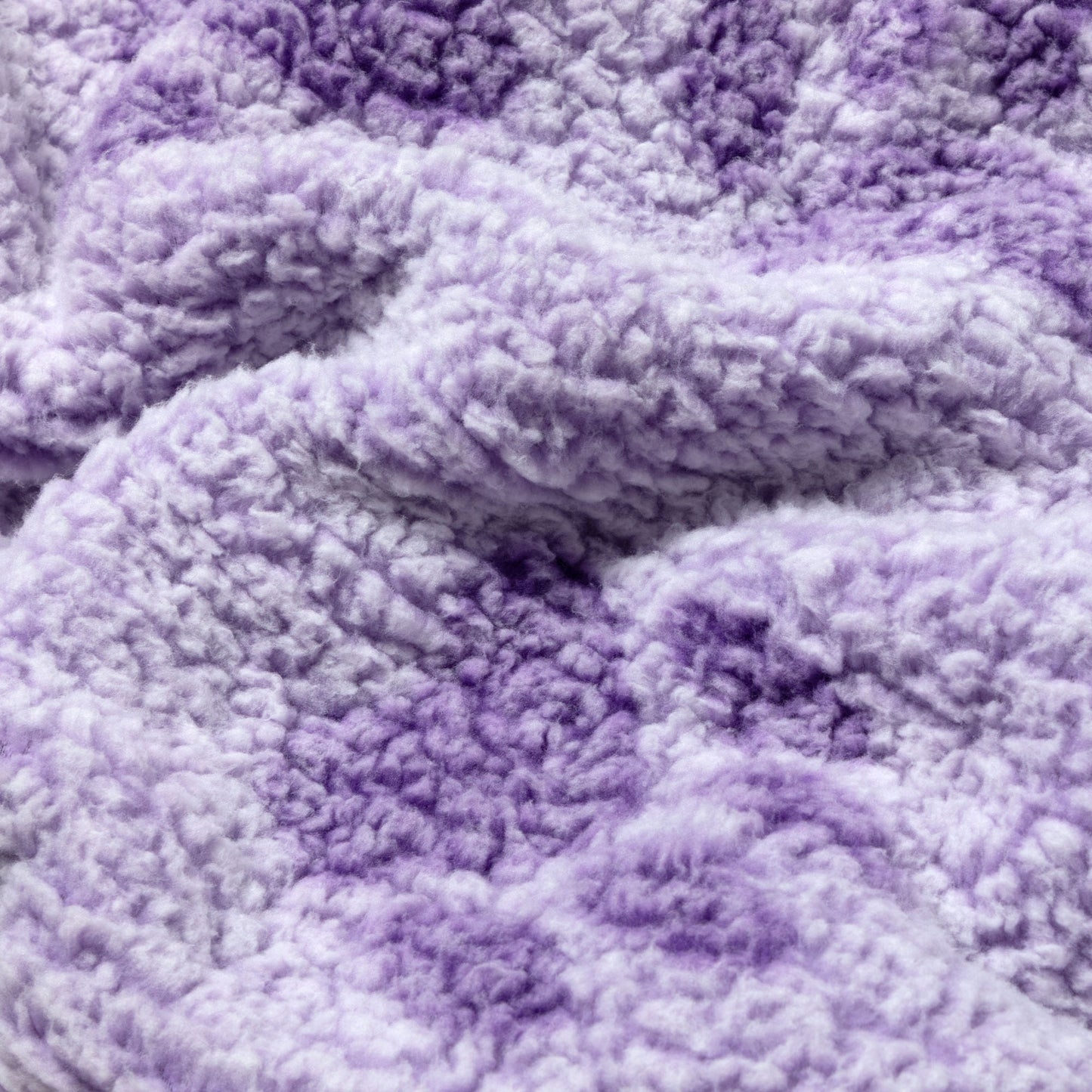 A close-up of a soft, plush sherpa fabric in a lavender and light purple gradient, showing the textured, fluffy material.
