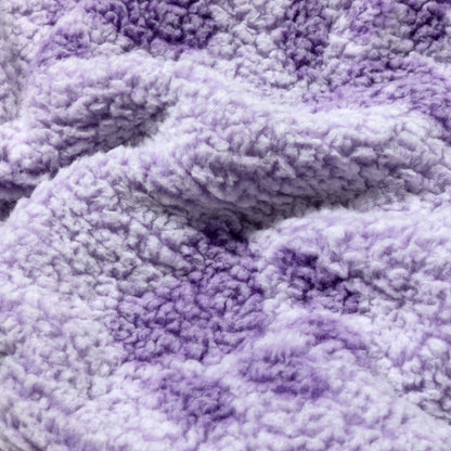 A close-up of a soft, plush sherpa fabric in a lavender and light purple gradient, showing the textured, fluffy material.