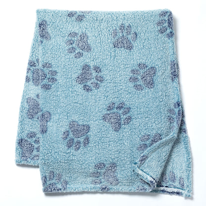 A light blue fleece blanket with a repeating dark blue paw print pattern, folded neatly on a white background.