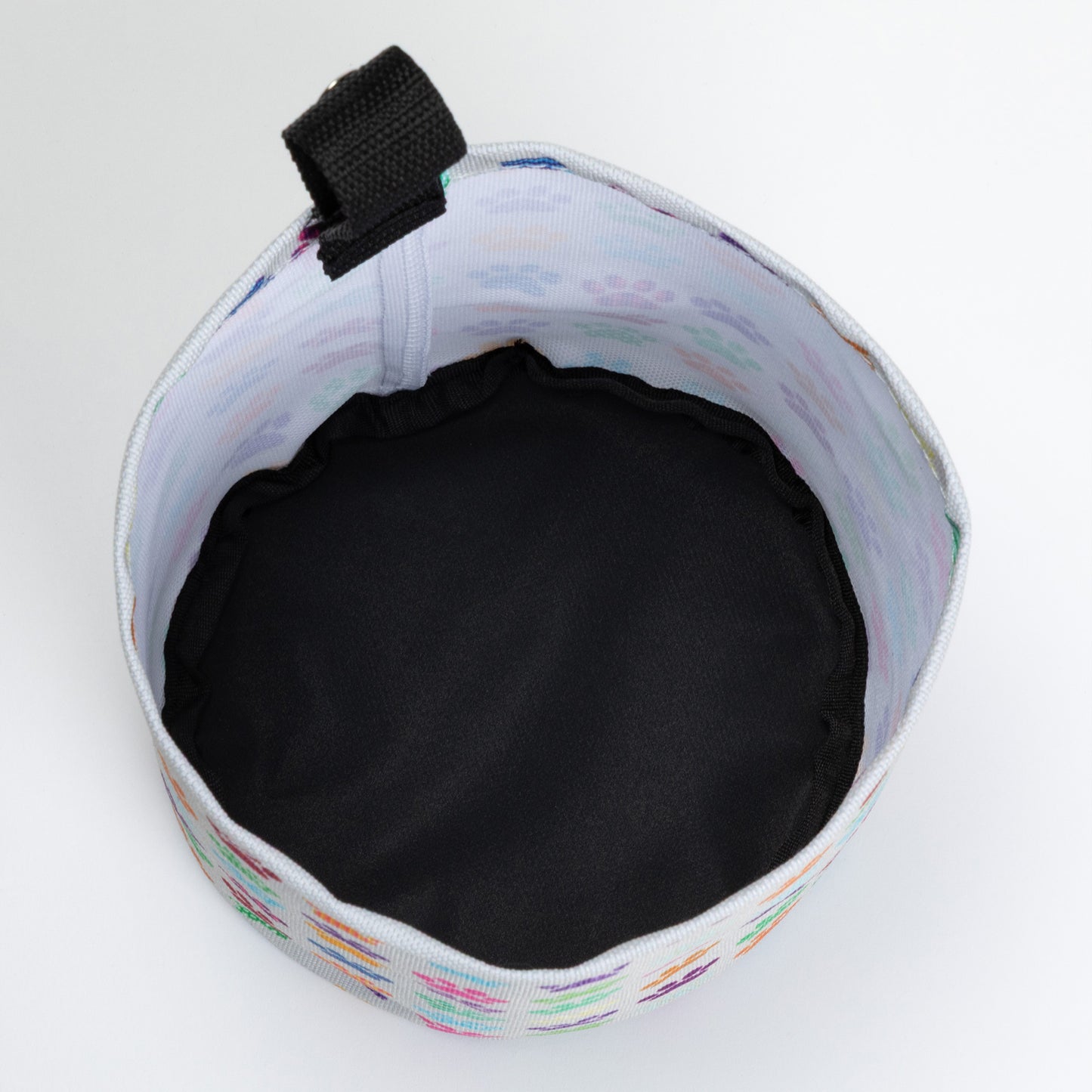 Collapsible car garbage holder with paw print pattern on a white background. Inside of fabric is white and the bottom is black. 