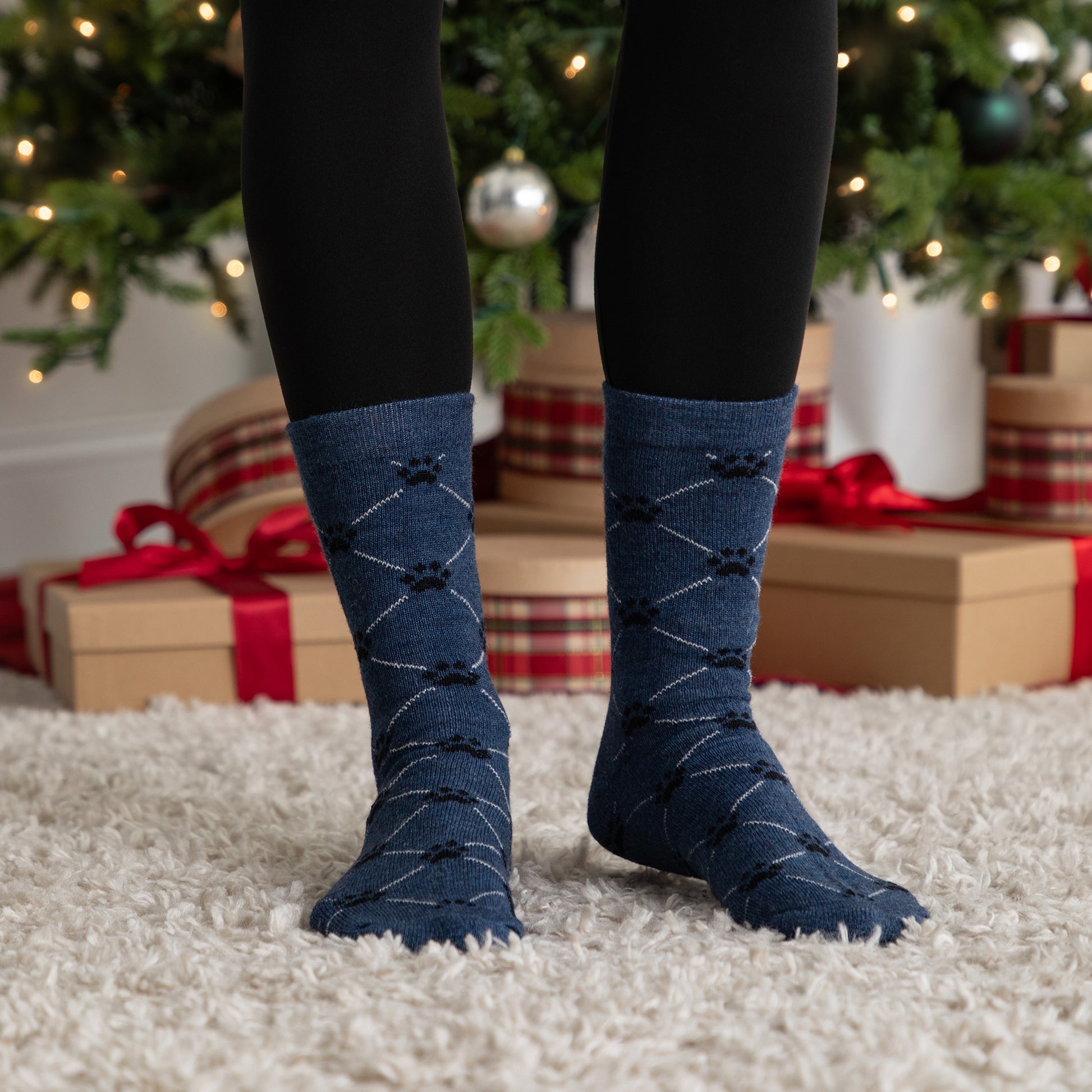 Person wearing blue argyle socks with a Christmas tree and presents in the background