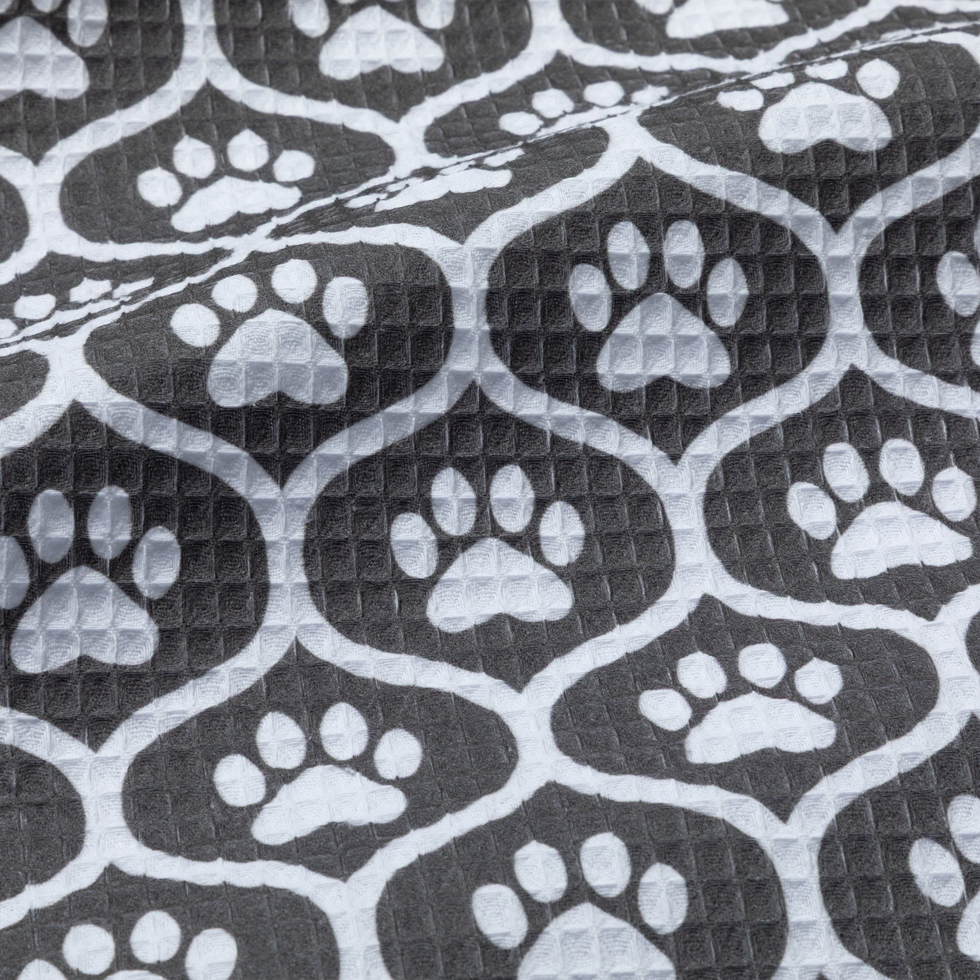 Patterned kitchen towel with white paw prints on a black background