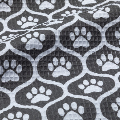 Patterned kitchen towel with white paw prints on a black background