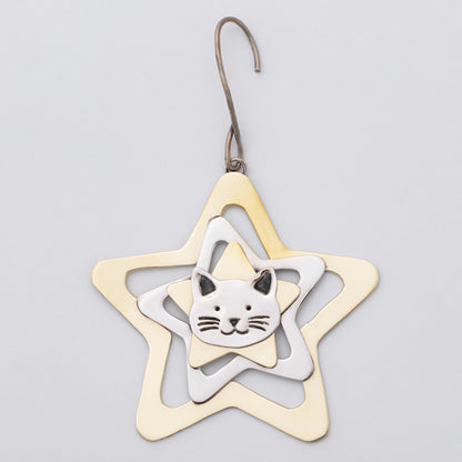 A metal ornament shaped like a five-pointed star with a small cat face in the center, suspended from a hook against a light gray background.