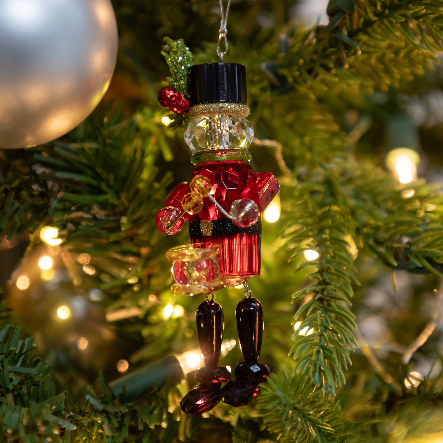 Decorative Christmas ornament shaped like a nutcracker hanging on a tree.