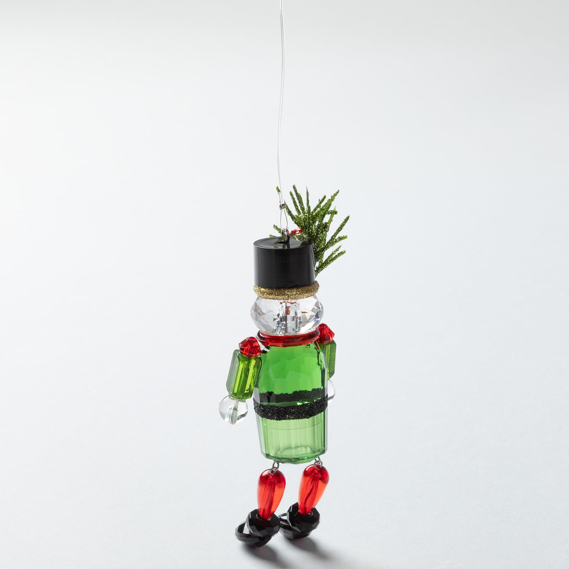 nutcracker ornament with black top hat and sparkly holly in the hat with a green body