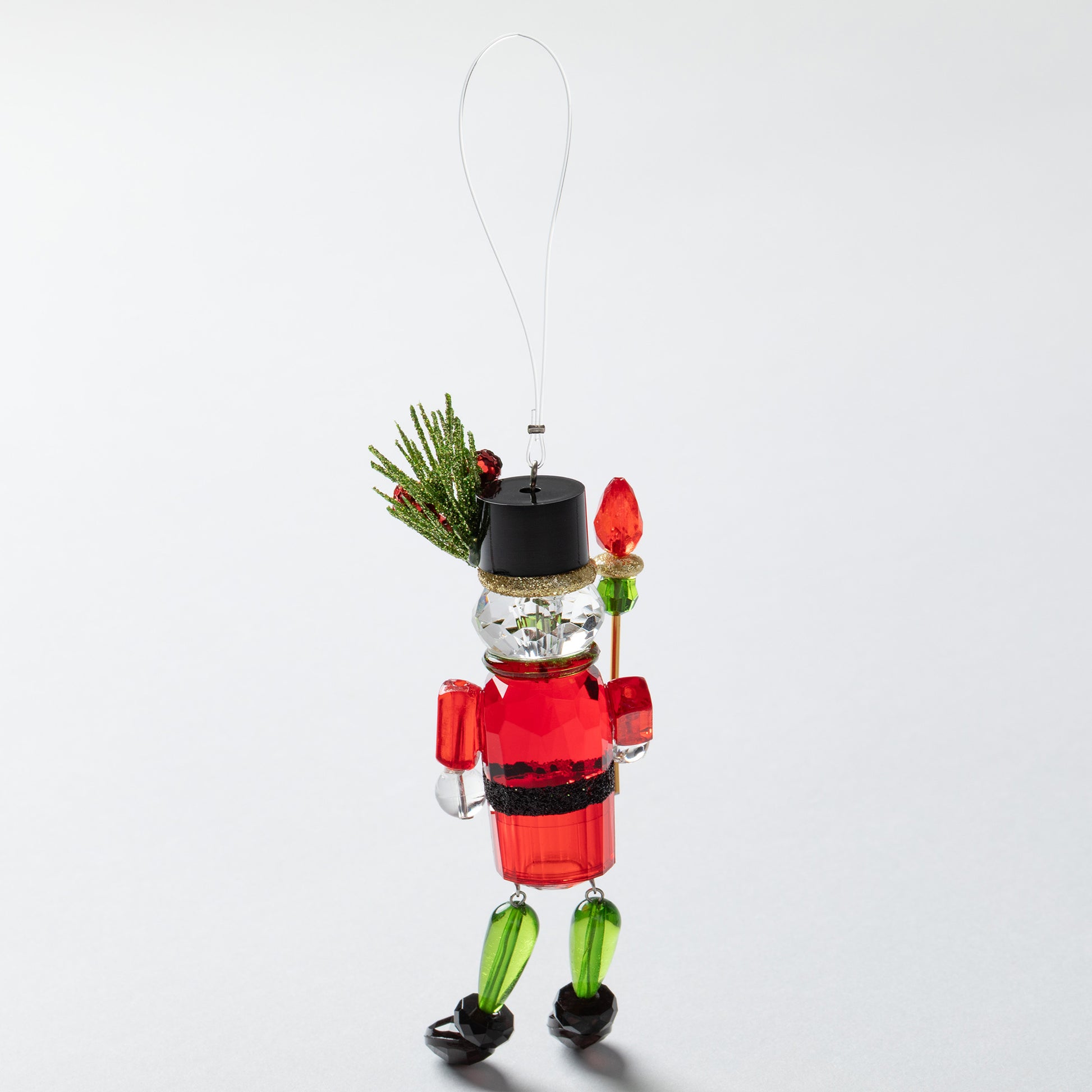 Decorative Christmas nutcracker ornament with holly on hat on a white background