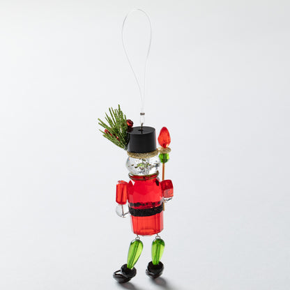 Decorative Christmas nutcracker ornament with holly on hat on a white background