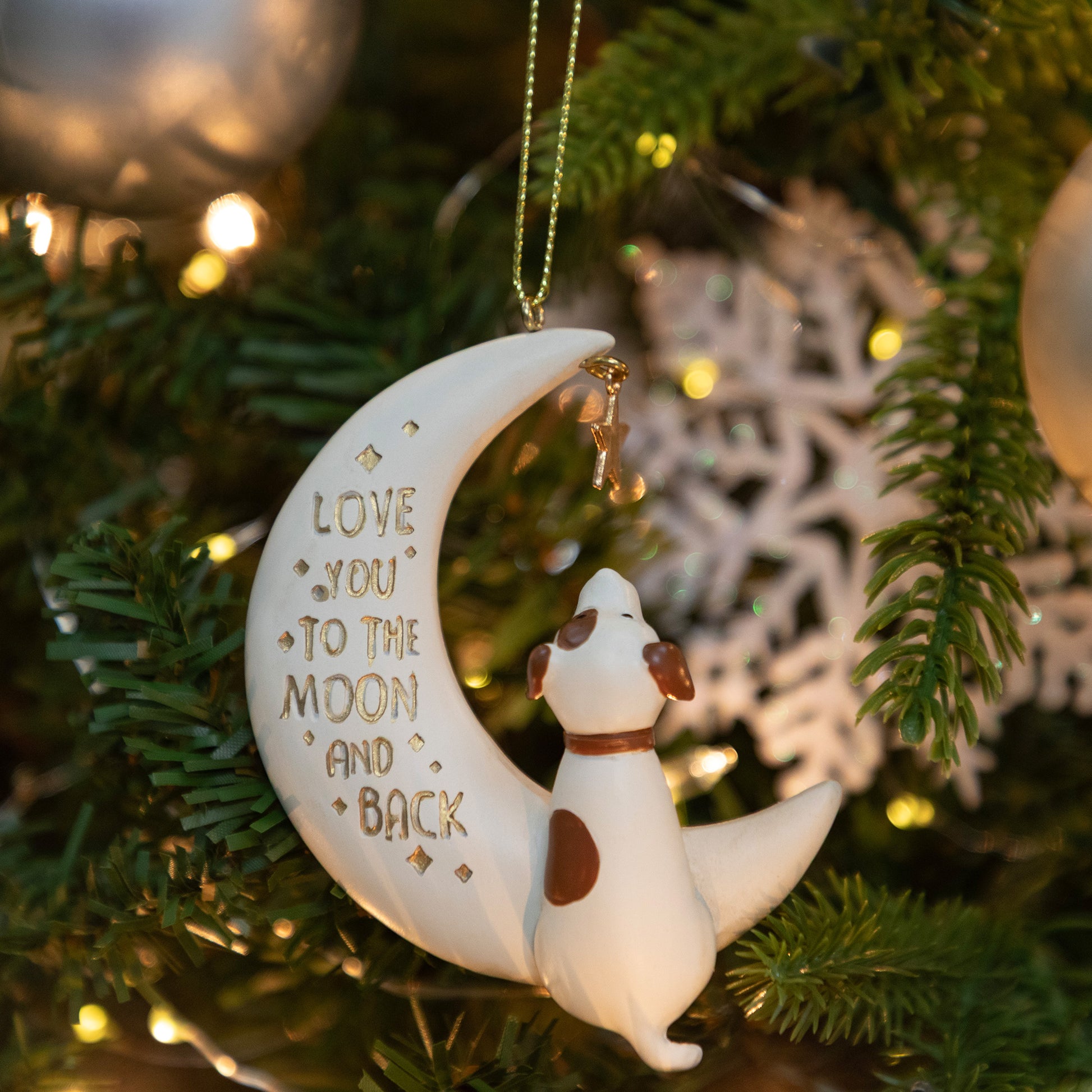 Decorative ornament with a dog on a moon, featuring the text 'Love you to the moon and back', hanging on a Christmas tree.