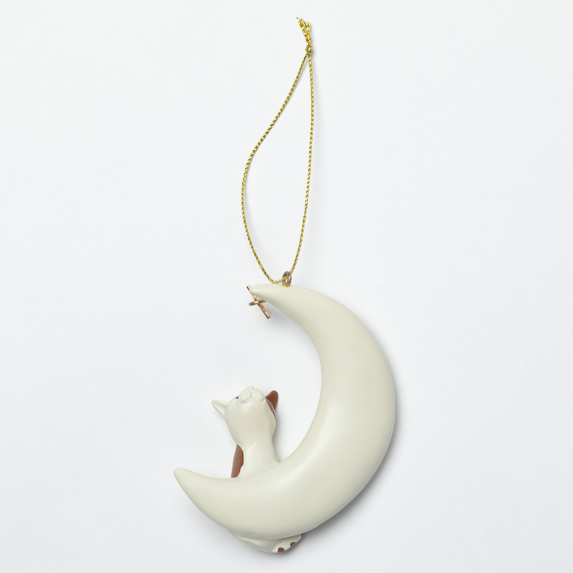 Decorative ornament of a cat lying on a crescent moon with a gold chain on a light gray background