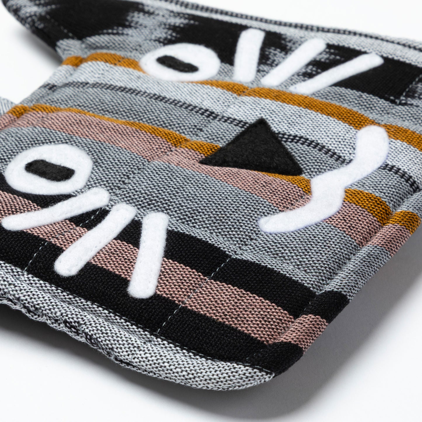 Close-up of a cat-themed pot holder with striped pattern on a white background
