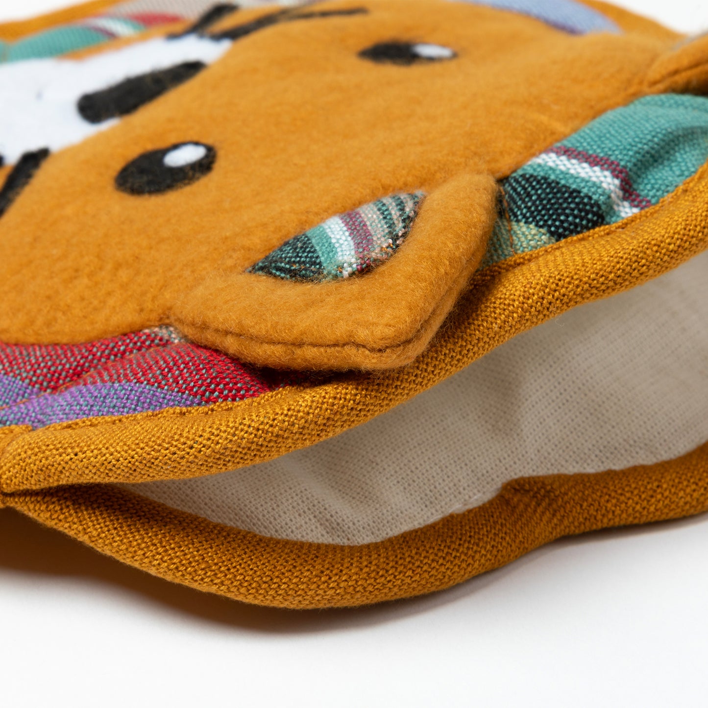 Close-up of a textured fabric pouch with colorful patterns on a white background