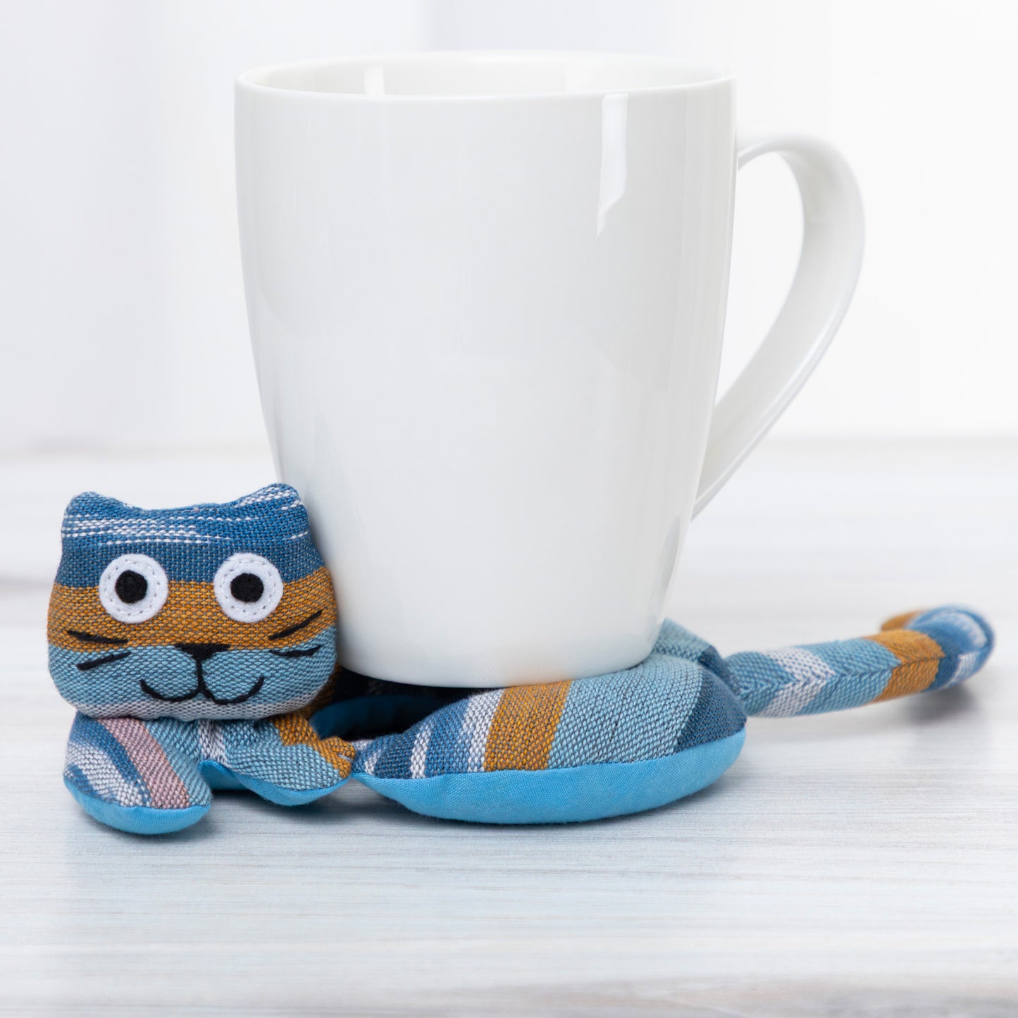  bStriped cat-shaped coaster on a light gray background with a white mug