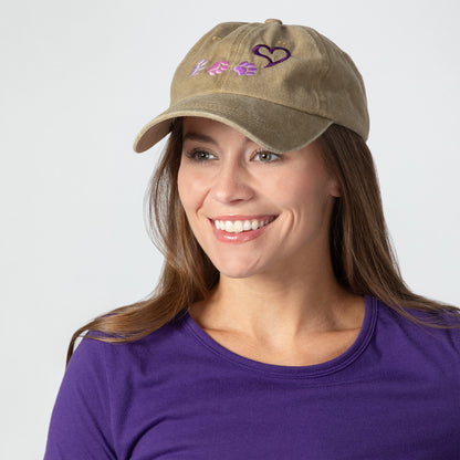 Woman wearing a tan cap with paws and a heart design on a white background