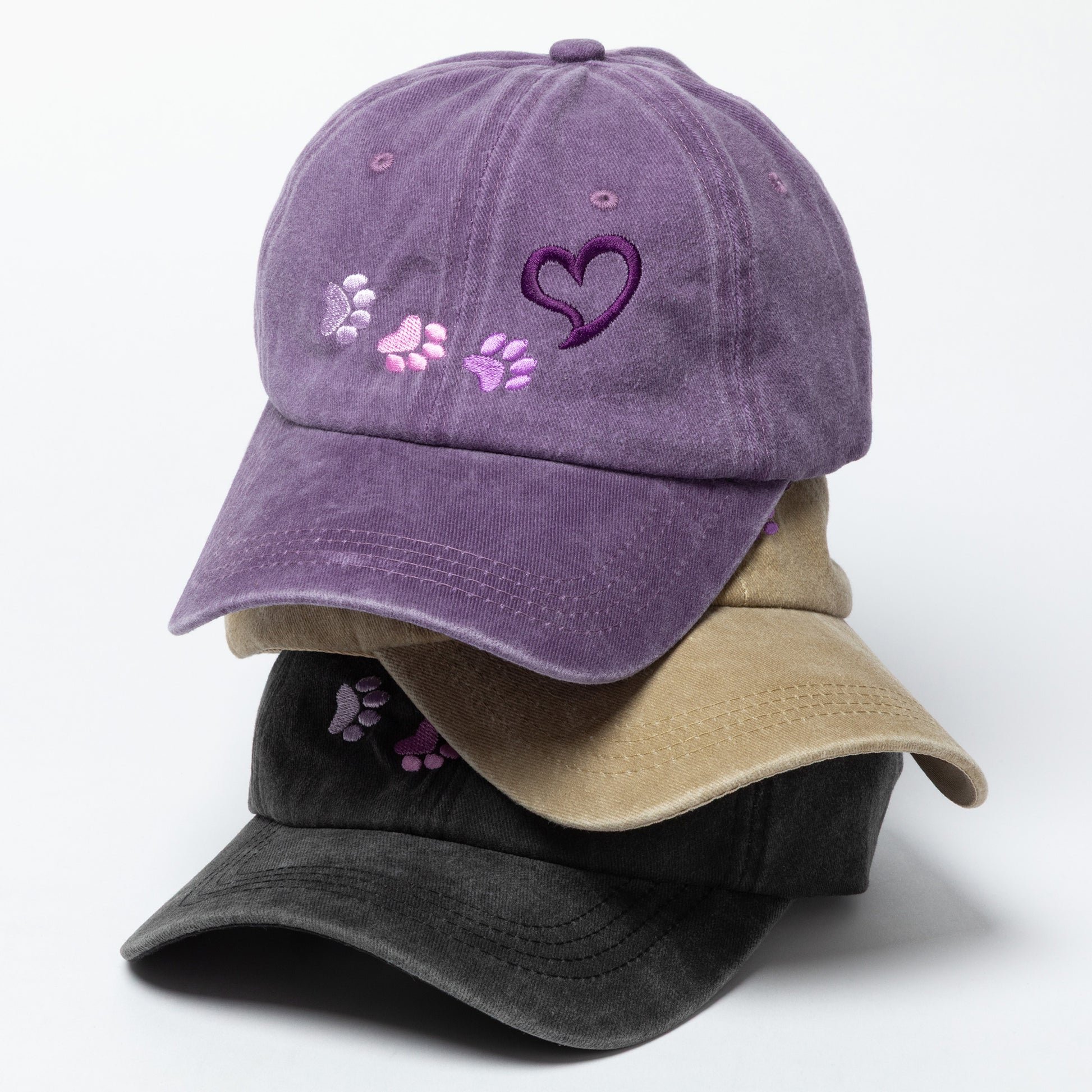 Purple baseball cap with paw prints and a heart design on a white background