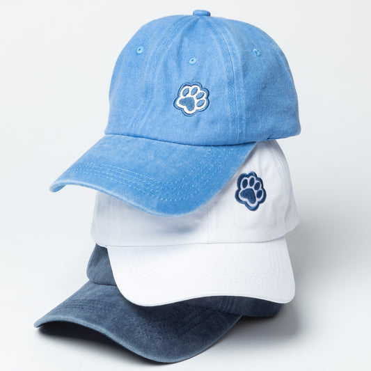 Three baseball caps, two blue and one white, with paw prints on a light gray background.