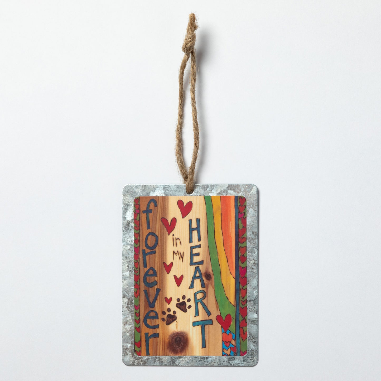 Decorative hanging ornament with "Forever in My Heart" text, hearts and paw prints on a wood background with a heart border on both sides with a rainbow design against a white background