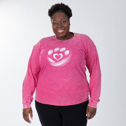 Person wearing a pink long-sleeve shirt with a heart design on a white background