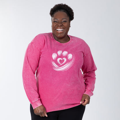 Woman wearing a pink long-sleeve shirt with a heart and paw print design on a white background