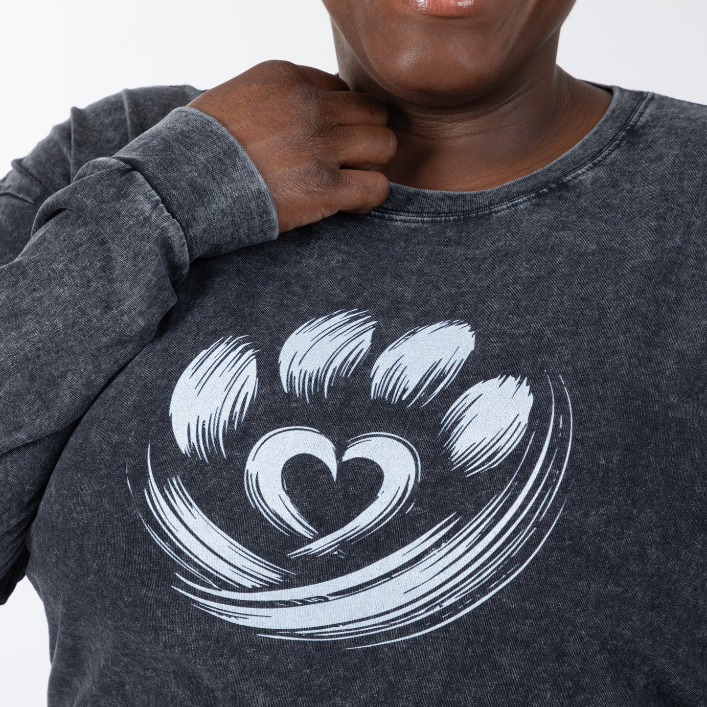 Person wearing a dark gray sweatshirt with a white paw print design on a plain background
