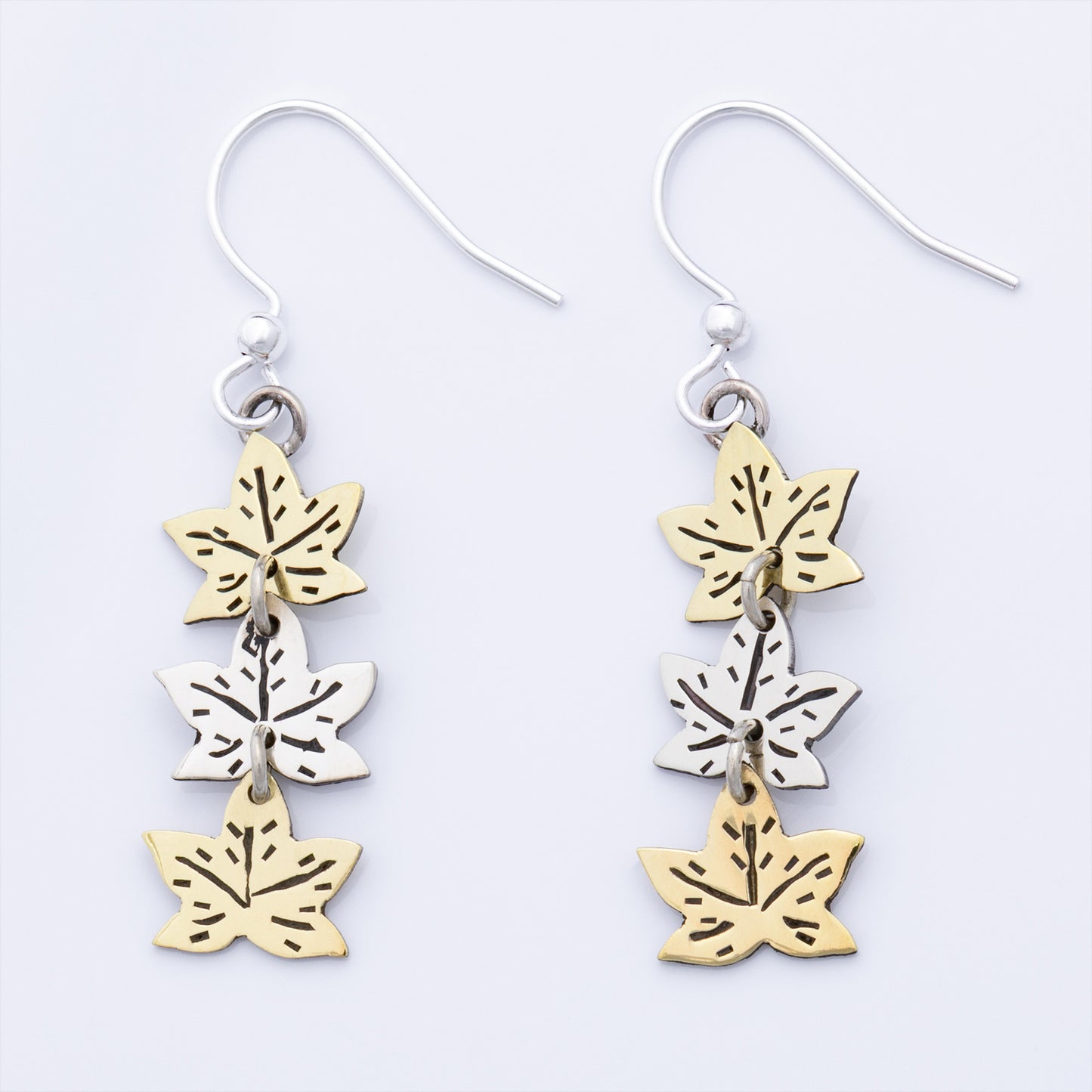 Pair of earrings with leaf-shaped charms on a white background
