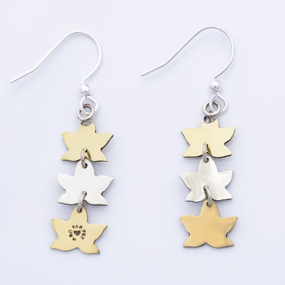 Backs of leaf-shaped earrings in gold and silver on a light gray background