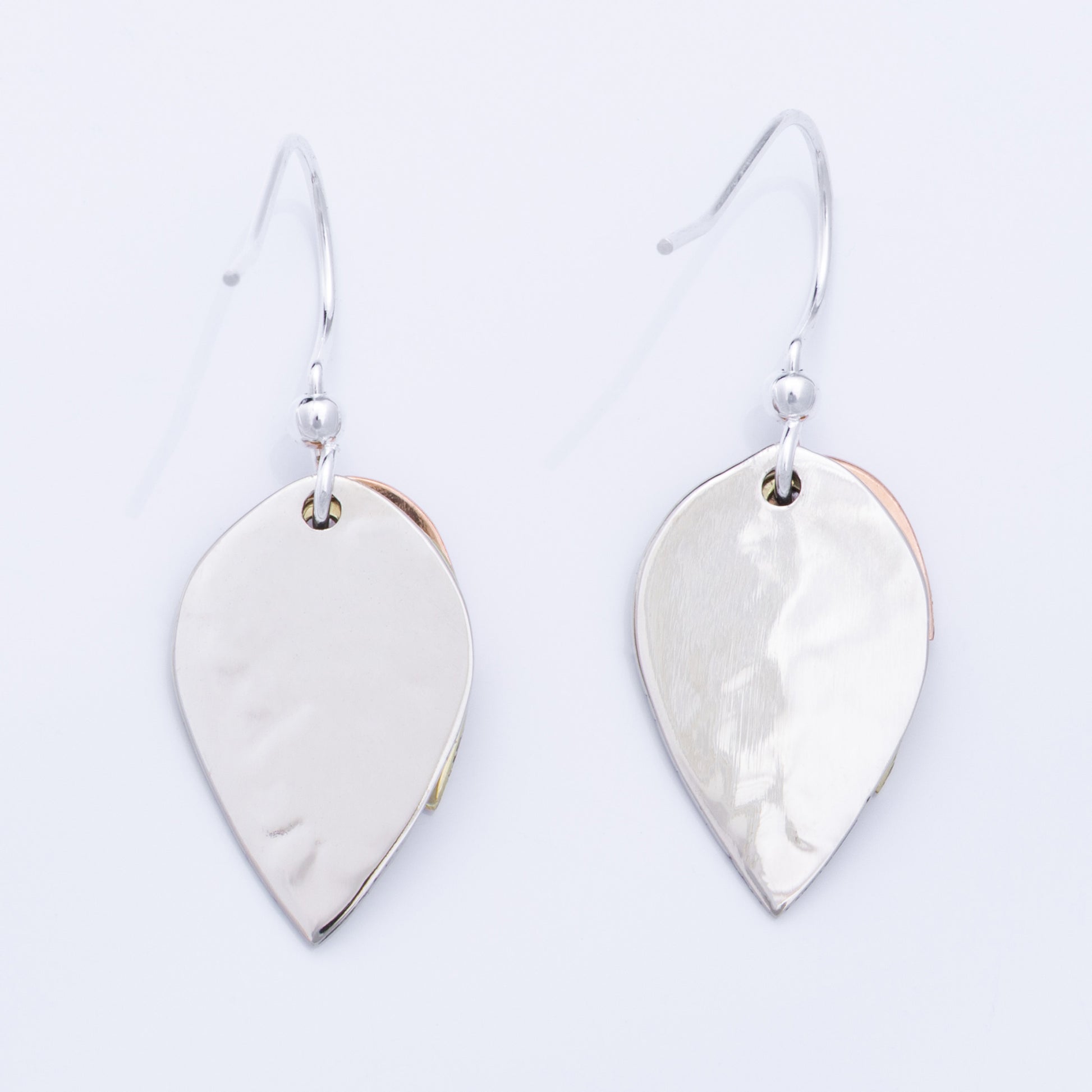 Backs of silver leaf-shaped earrings on a light gray background