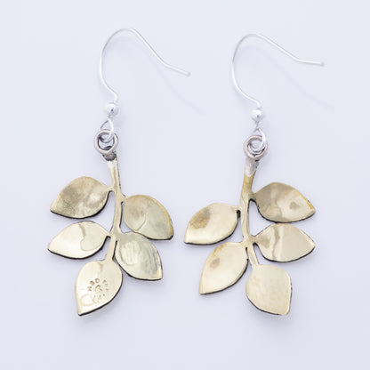 The backs of brass leaf-shaped earrings on a white background