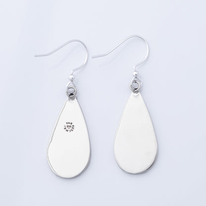 The back of silver teardrop earrings on a light gray background.