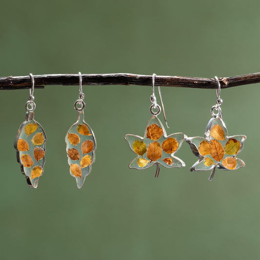 Pair of leaf-shaped earrings with autumn leaf design on a branch against a green background