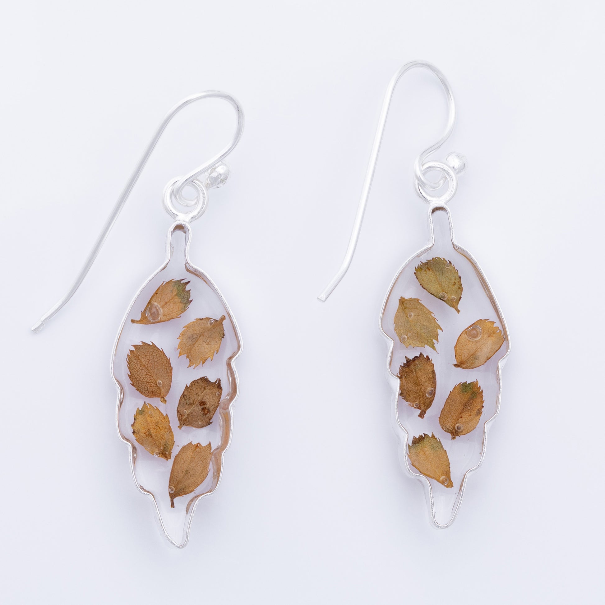 Pair of leaf-shaped earrings with brown and green leaves on a white background