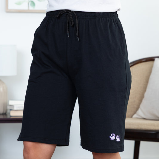 Black shorts with a paw print design on a person standing indoors.