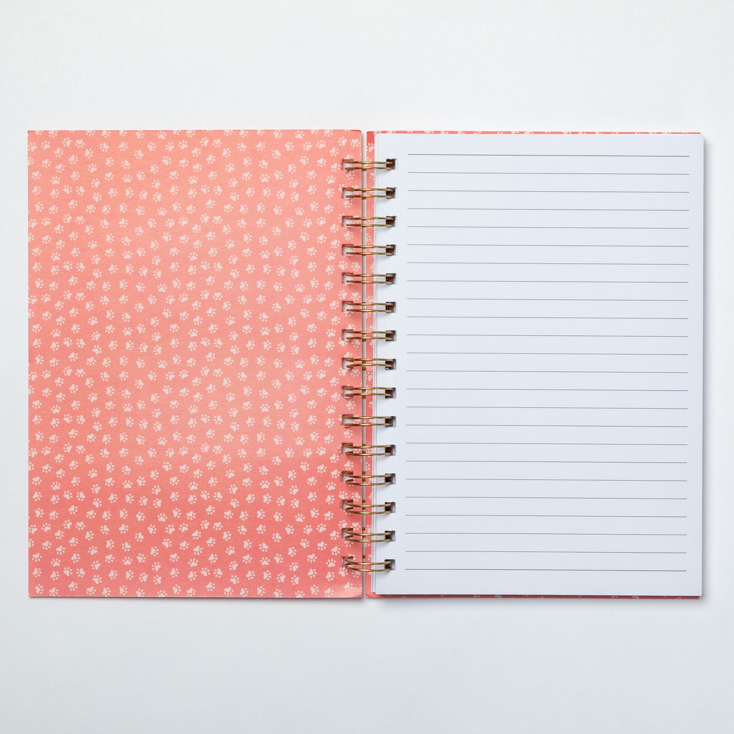 Open notebook with pink dotted cover and white lined pages on a light gray background