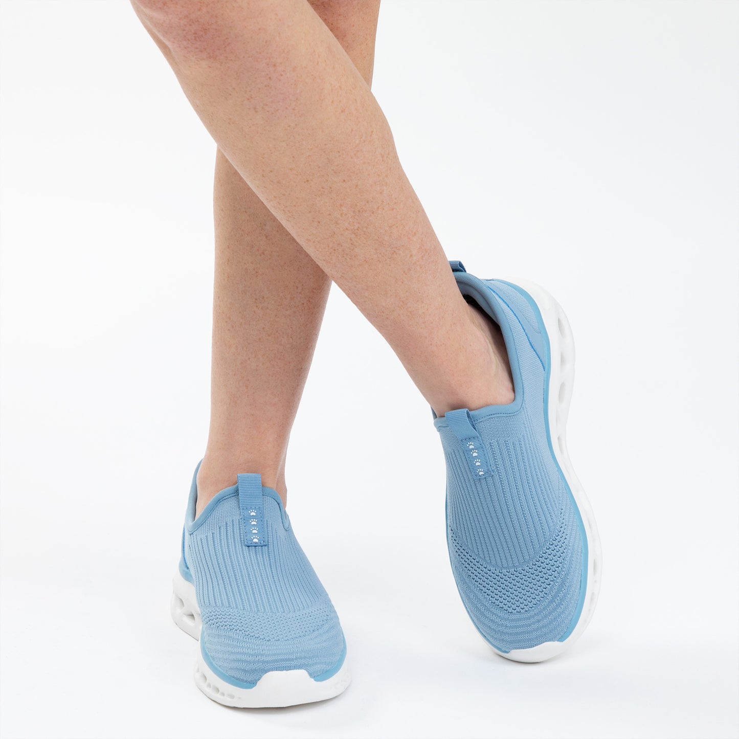 Blue slip-on shoes worn by a person on a white background