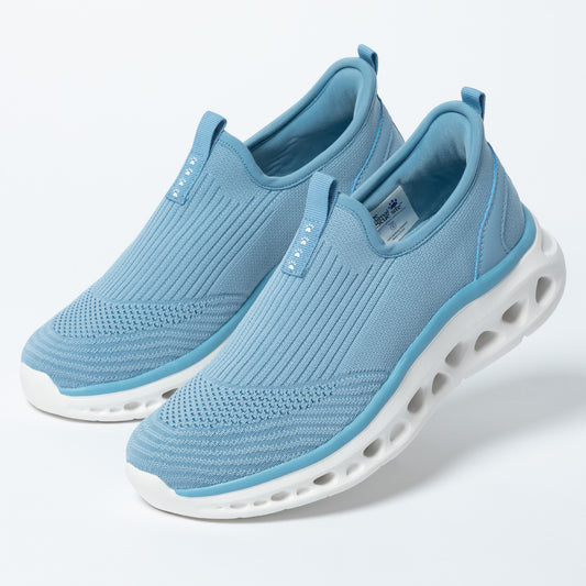 Pair of light blue slip-on shoes with white soles on a light gray background