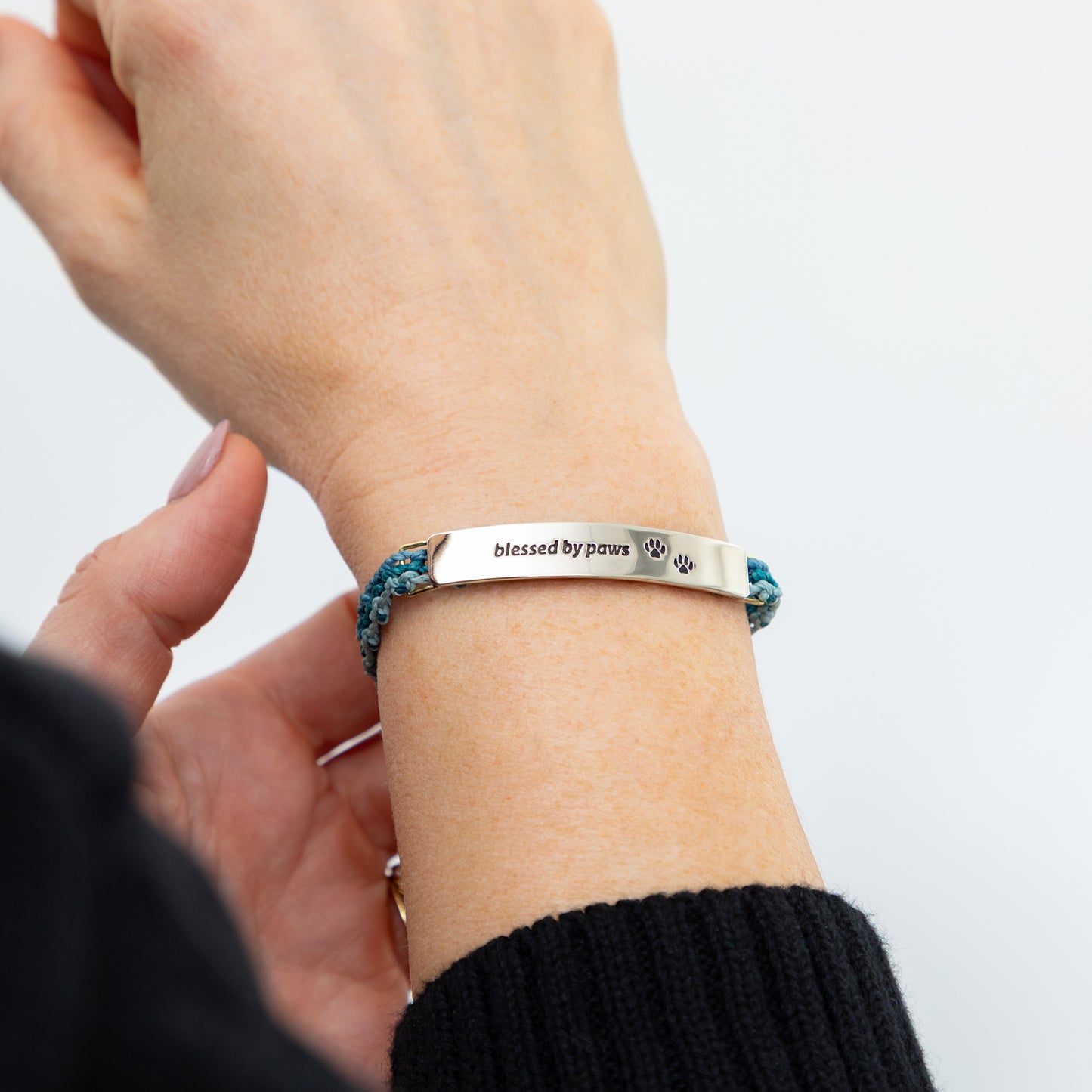 Bracelet with 'blessed by paws' text on a wrist against a light background