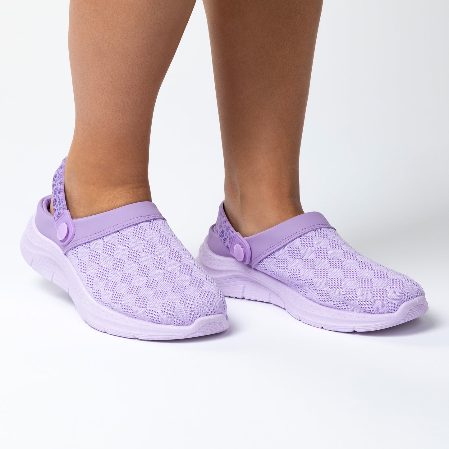 Purple clogs with a knitted upper worn by a person on a white background