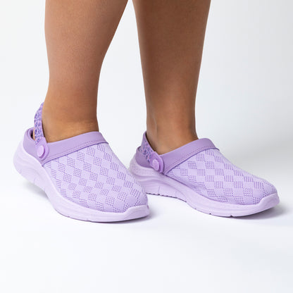 Purple clogs with a knitted upper worn by a person on a white background