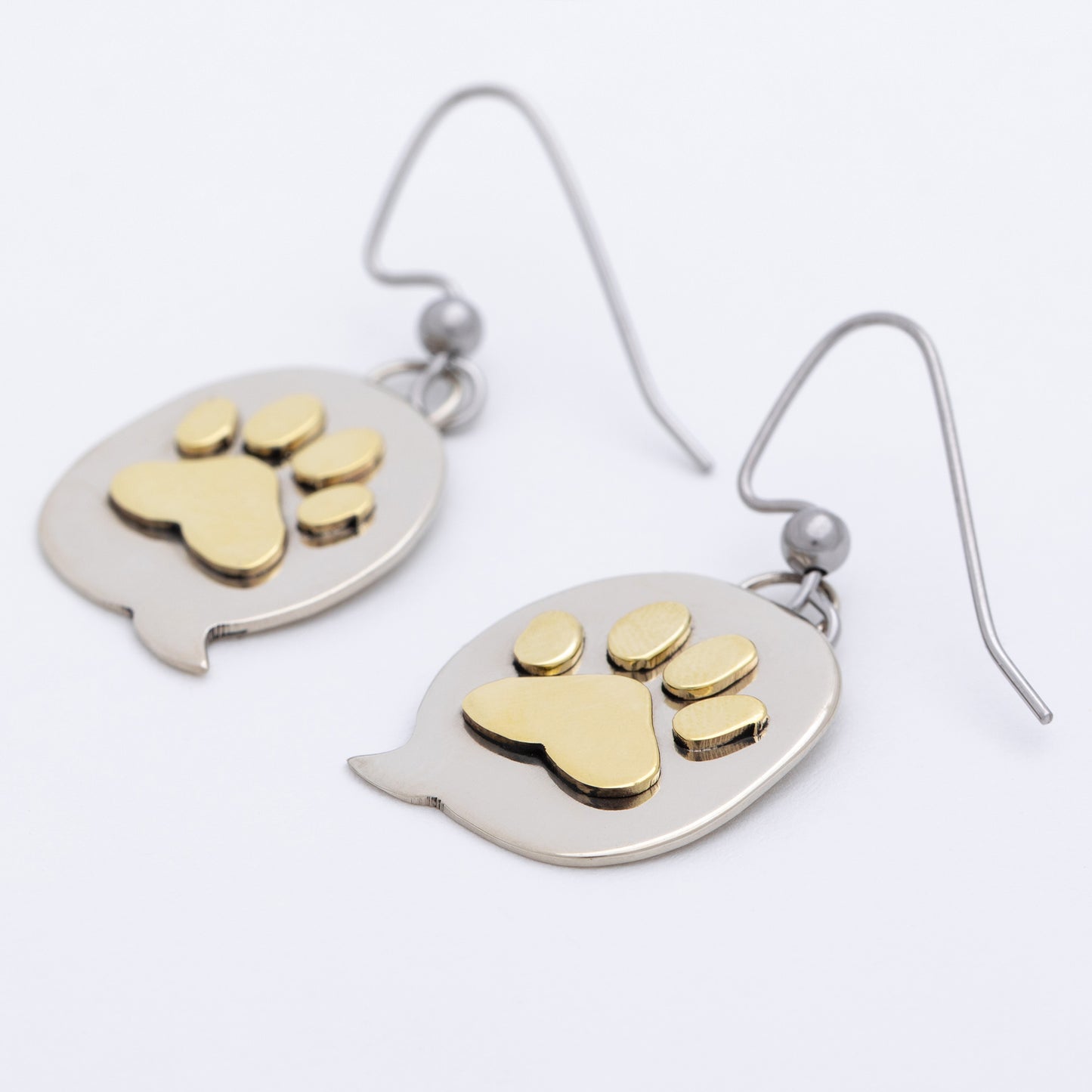 Pair of earrings with brass paw prints on silver oval backgrounds.