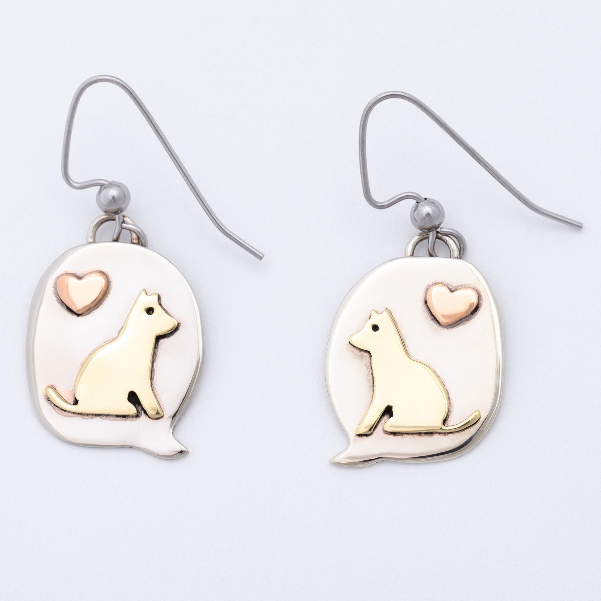 Pair of earrings with dog and heart designs on a light background