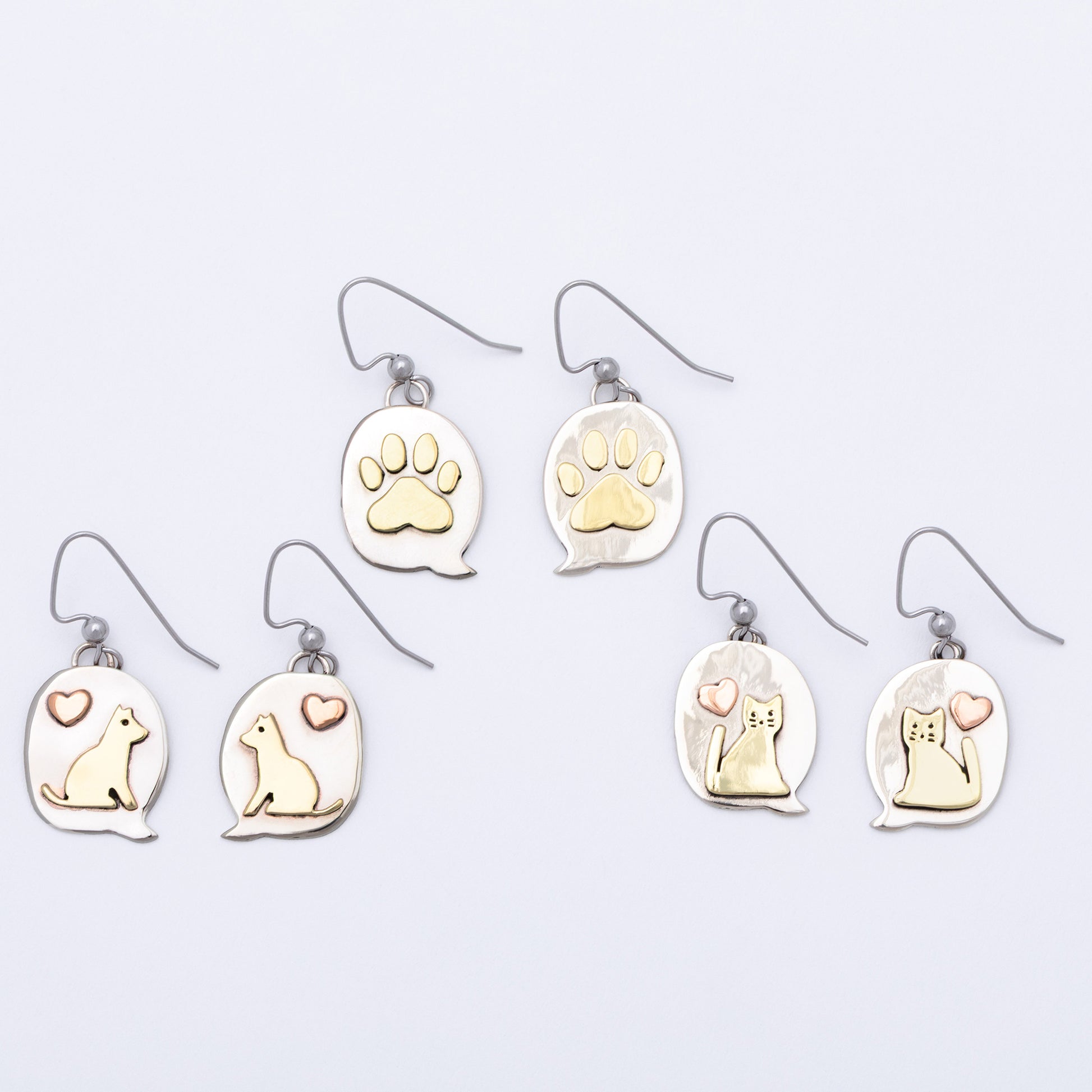 Set of earrings with paw prints and animal illustrations on a light gray background.