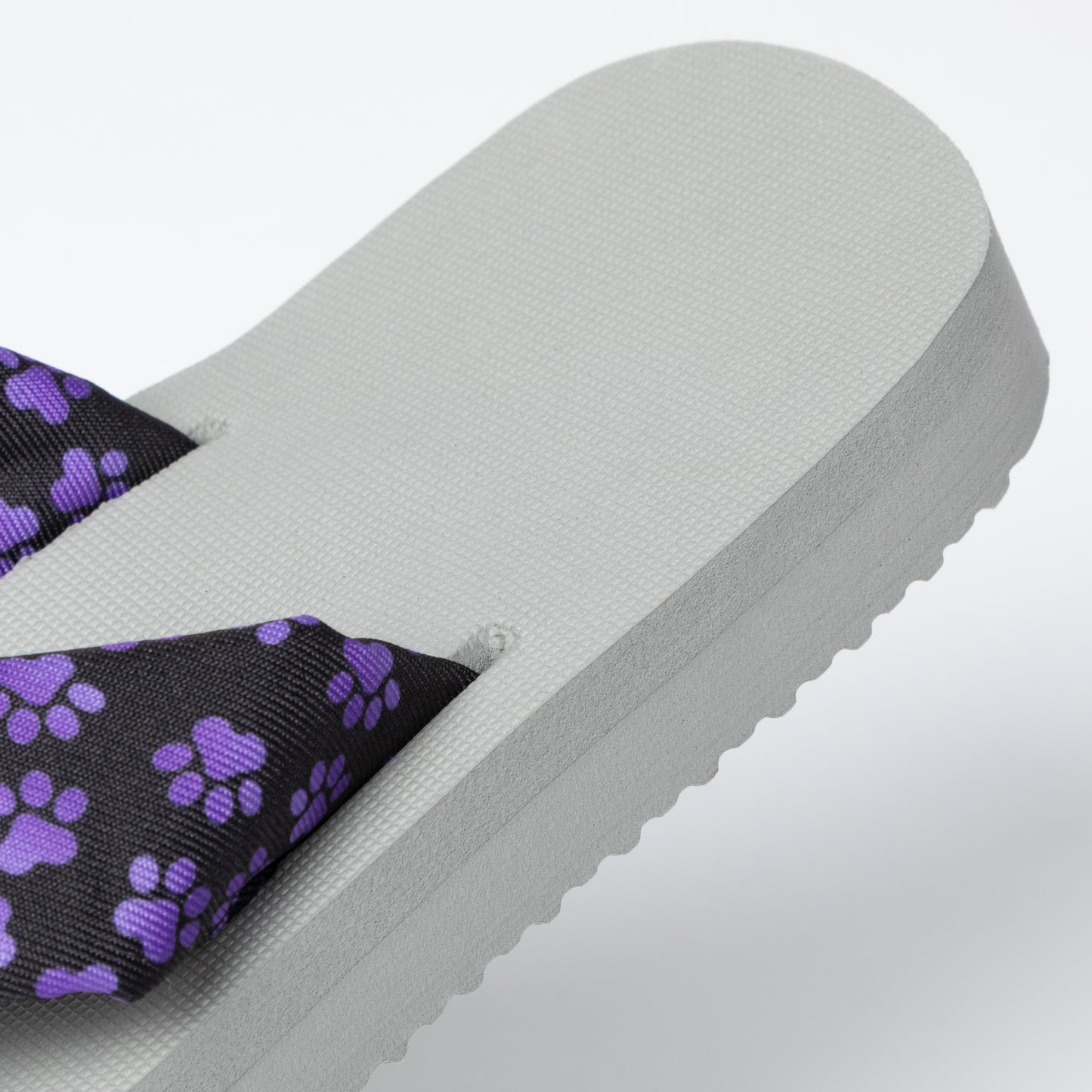 Gray sandal with purple paw print strap on a light gray background