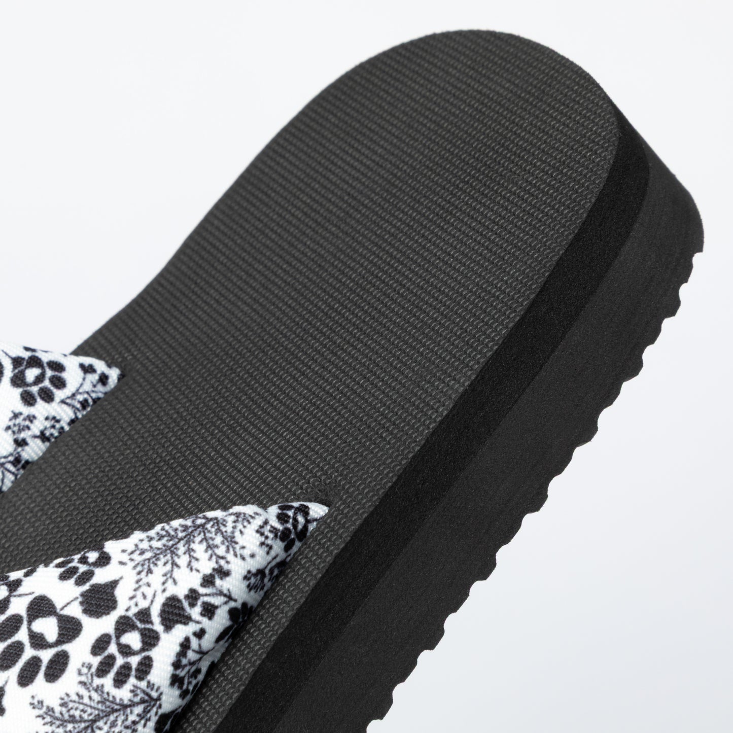 Black sandal with floral pattern on a light gray background