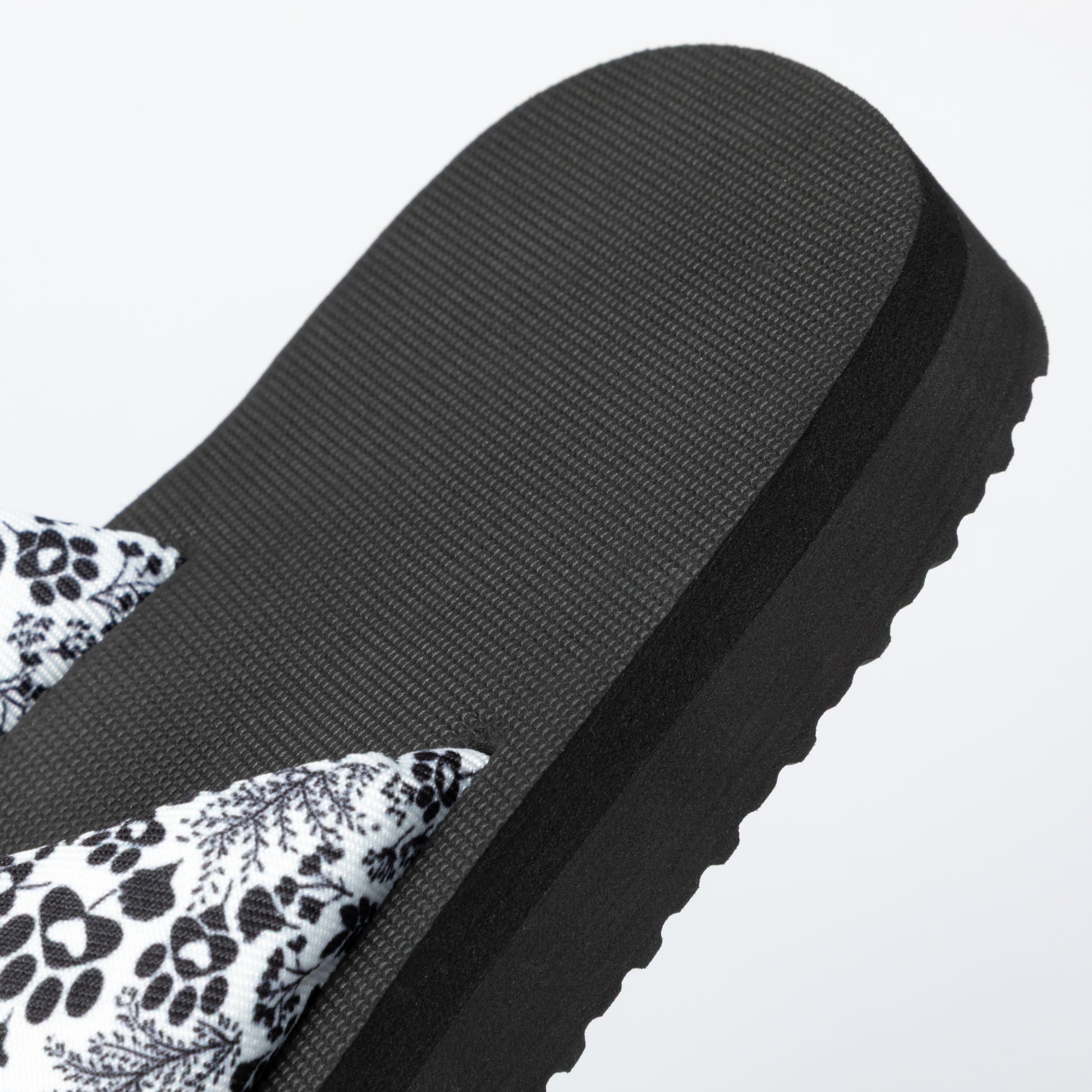 Black sandal with floral pattern on a light gray background